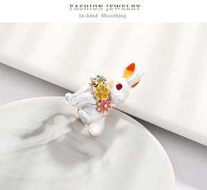 Detail of bunny brooch with multi-color enamel flowers and red zircon eye on stone plate