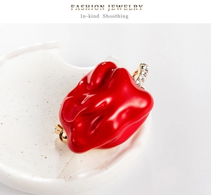 Gros plan d'une broche piment en émail rouge avec strass brillants sur un plat en céramique