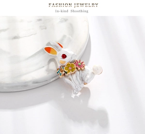 Exquisite white enamel rabbit brooch featuring colorful floral details and a pearl tail