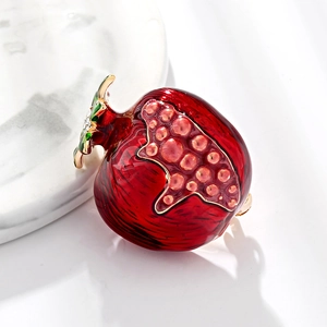 Spilla creativa a forma di melograno con smalto rosso e cristalli su marmo bianco
