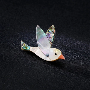 Exquise broche d'oiseau avec incrustation d'abalone irisée sur un fond sombre
