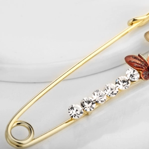Elegante spilla a balia dorata con intarsio di strass scintillanti e ciondolo a farfalla