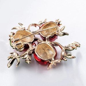 Retro pomegranate brooch with gold finish and red enamel detailing on a white background
