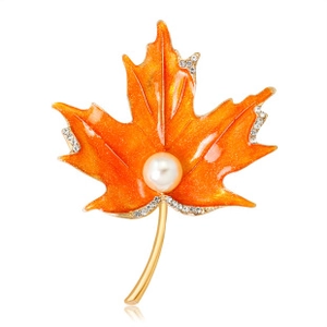 Detailed macro of orange maple leaf brooch with white pearl and sparkling rhinestones