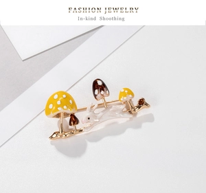 Detail of bunny and mushroom enamel brooch with polished gold-tone metal base and texture