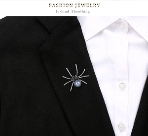Macro detail of a creative spider brooch with a large grey pearl on a black suit lapel