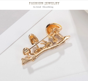 Detail of bunny and mushroom brooch back with golden metal texture and safety pin clasp