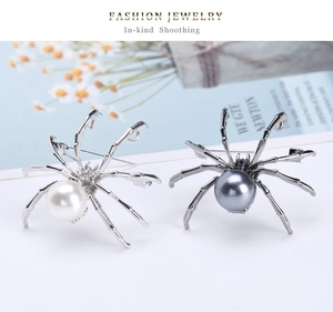 Macro detail of insect spider brooches featuring large pearls in silver and gunmetal finishes
