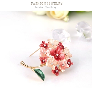 Detailed macro view of enamel flower brooch with rhinestones and green leaf decor