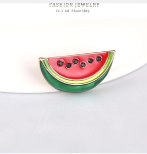 Detail of a watermelon brooch with red enamel, green rind, and black crystal seeds