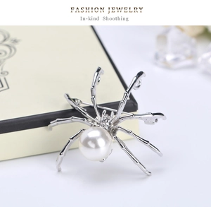 Macro view of silver spider brooch with white pearl and rhinestone accents