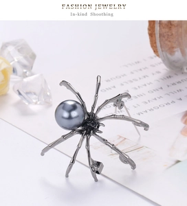 Macro shot of spider brooch with grey pearl and black zircon crystals on vintage paper