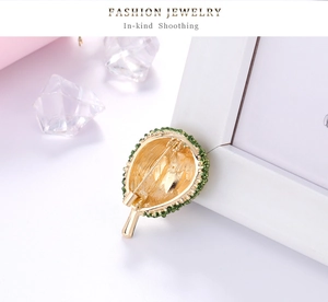 Detailed close-up of durian-shaped brooch with golden finish and green crystals