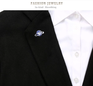 Detailed view of a silver globe enamel brooch pinned on a stylish black suit lapel