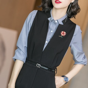 Elegant floral brooch with red petals and green leaves on a black suit lapel