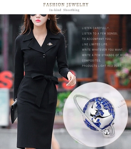 Detailed view of a planet-shaped brooch with blue enamel on a black wool coat lapel