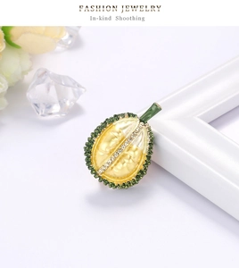 Detail of durian brooch with yellow pulp and green rhinestone crust on white frame