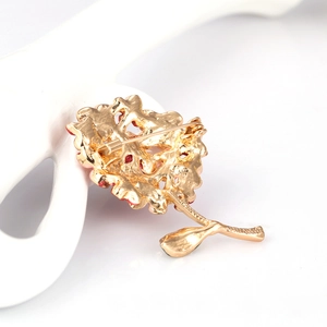 Elegant gold flower brooch with red enamel and pearl details in diagonal view