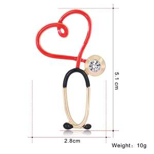 Detailed view of gold stethoscope brooch with red heart, rhinestone, and size dimensions