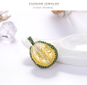 Close-up of durian-shaped brooch with yellow enamel texture and white sparkling crystals