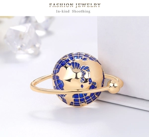 Detail shot of golden earth globe charm with blue enamel coating and a satin finish