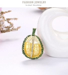Detailed view of gold durian brooch featuring yellow enamel pulp and crystal accents