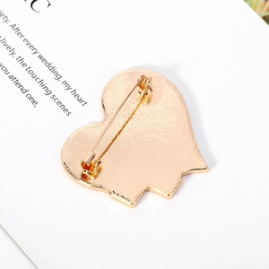 Detail view showing the secure rotating safety pin and gold heart brooch structure