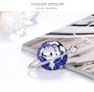 Detailed close-up of fashion planet globe brooch with blue enamel and silver metal rings