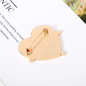 Detail of gold heart brooch back with secure rotating safety pin and matte metal texture