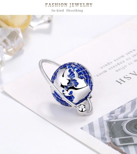 Detailed close-up of a silver planet brooch with blue enamel and longitude grid details