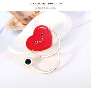 Détail macro de la broche stéthoscope avec cœur en émail rouge et métal doré