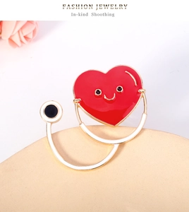 Détail d'une broche stéthoscope cœur rouge avec finition dorée et émail souriant
