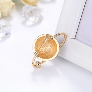 Golden planet globe brooch with metal clasp pin back on decorative background