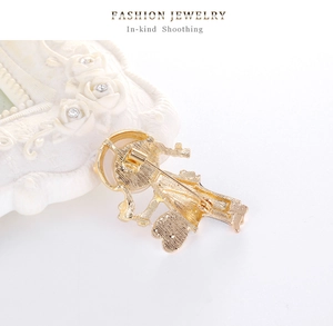 Detail showing the back of the golden girl brooch with a secure safety pin closure