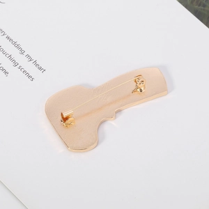 Macro detail of the gold-plated brooch back with safety pin clasp and frosted texture
