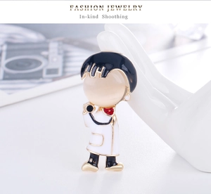 Detailed macro view of a cute cartoon doctor brooch with a yellow cat eye stone head