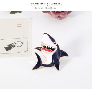 Detail of shark enamel brooch with gold-tone polished edges and blue dynamic design