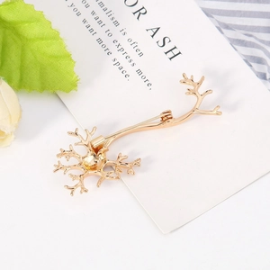 Detailed macro view of a gold neuron cell brooch placed on a decorative art card