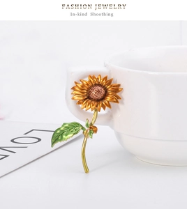 Détail d'une broche tournesol aux pétales dorés accrochée à une tasse en porcelaine
