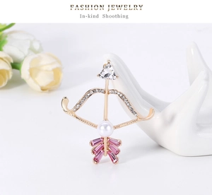 Detail of cupid bow brooch with pink crystals and white pearl on hand display
