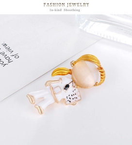 Detail of cartoon girl brooch featuring golden alloy, white enamel and opal stone