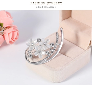 Détail d'une broche fleur argentée avec opales et strass brillants sur une boîte à bijoux