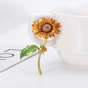 Broche de girasol artístico con pétalos dorados y hojas verdes en taza blanca
