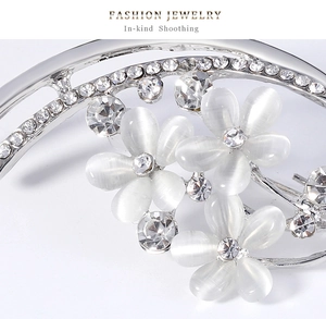 Détail macro d'une broche fleur en opale avec strass brillants et base en alliage