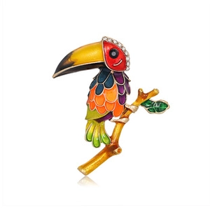 Vue détaillée de la broche toucan en émail coloré et strass sur une branche dorée