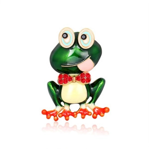 Détail de la broche grenouille en émail vert avec nœud en strass rouge et design créatif