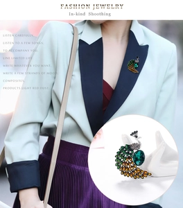 Détail de broche paon avec pierres vertes et strass sur un blazer vert menthe