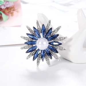 Anello girasole con cristalli blu e perla bianca esposto su supporto a forma di mano