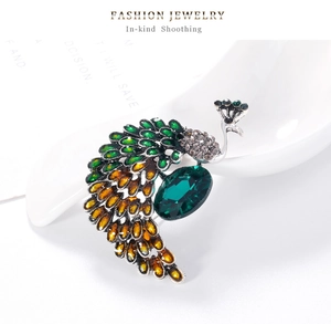 Vue détaillée d'une broche paon vintage avec cristaux verts et cadre en métal argenté