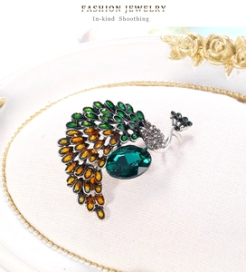 Vue détaillée de la broche paon vintage avec pierre émeraude et finitions en émail coloré